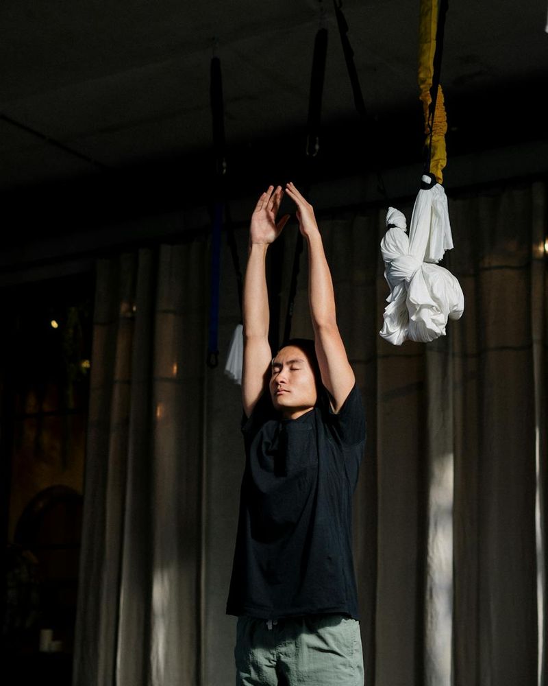 Person practicing fluid yoga movements in a dark studio